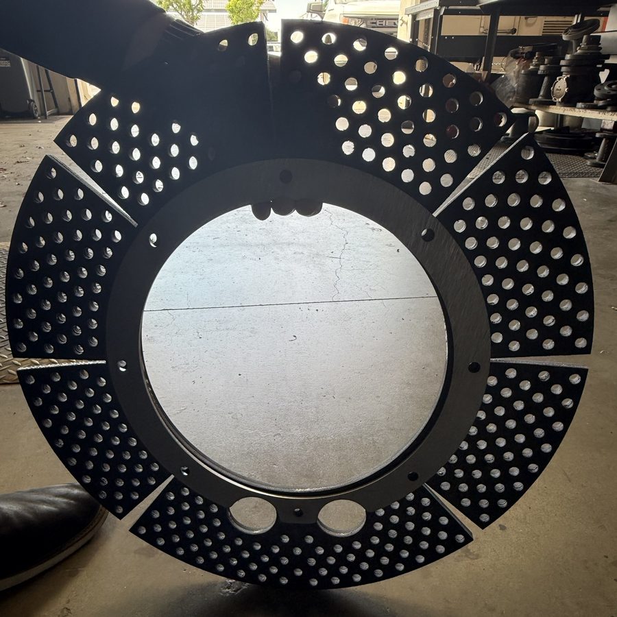 A fabricated EAD disc in the shop: eight black perforated rubber segments under a steel hub ring with two ports